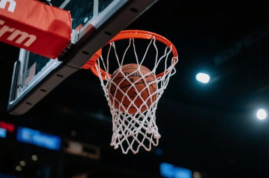 Close-up of a basketball swishing through a net under dramatic arena lighting